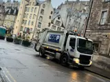 Loop Recycling truck mid-waste collection in Edinburgh. The truck features the company branding and logo, set against an Edinburgh city backdrop.